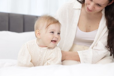 Photo of Cute little baby and mother on bed indoors, closeup