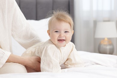 Photo of Cute little baby and mother on bed indoors, closeup