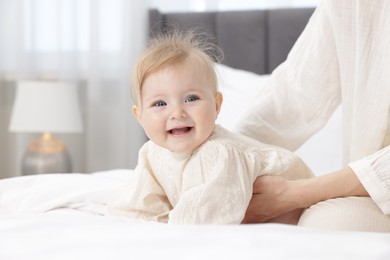 Photo of Cute little baby and mother on bed indoors, closeup