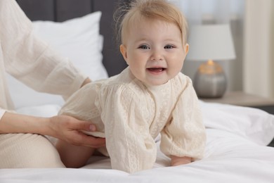 Photo of Cute little baby and mother on bed indoors, closeup