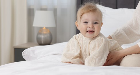 Photo of Cute little baby and mother on bed indoors, closeup. Space for text