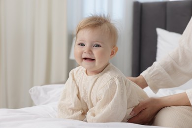 Photo of Happy little baby and mother on bed indoors, closeup