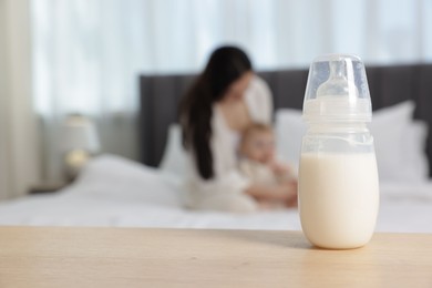 Photo of Mother with her little baby indoors, focus on bottle of milk
