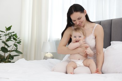 Photo of Smiling mother with her little baby on bed at home. Space for text