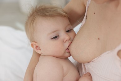 Photo of Mother breastfeeding her cute little baby indoors, closeup