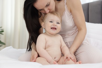 Photo of Mother kissing her little baby on bed at home