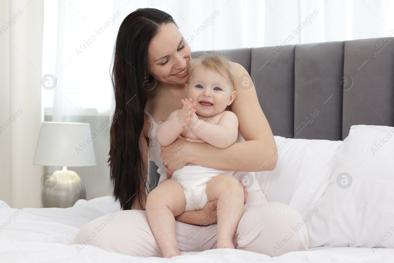Smiling mother with her little baby on bed at home Photo of Smiling mother with her little baby on bed at home