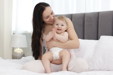 Photo of Smiling mother with her little baby on bed at home