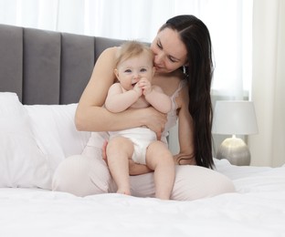 Photo of Smiling mother with her little baby on bed at home