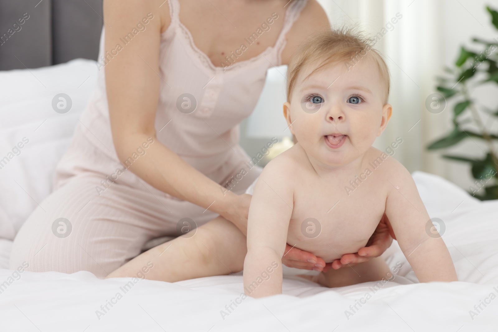 Cute little baby and mother on bed indoors, closeup Photo of Cute little baby and mother on bed indoors, closeup