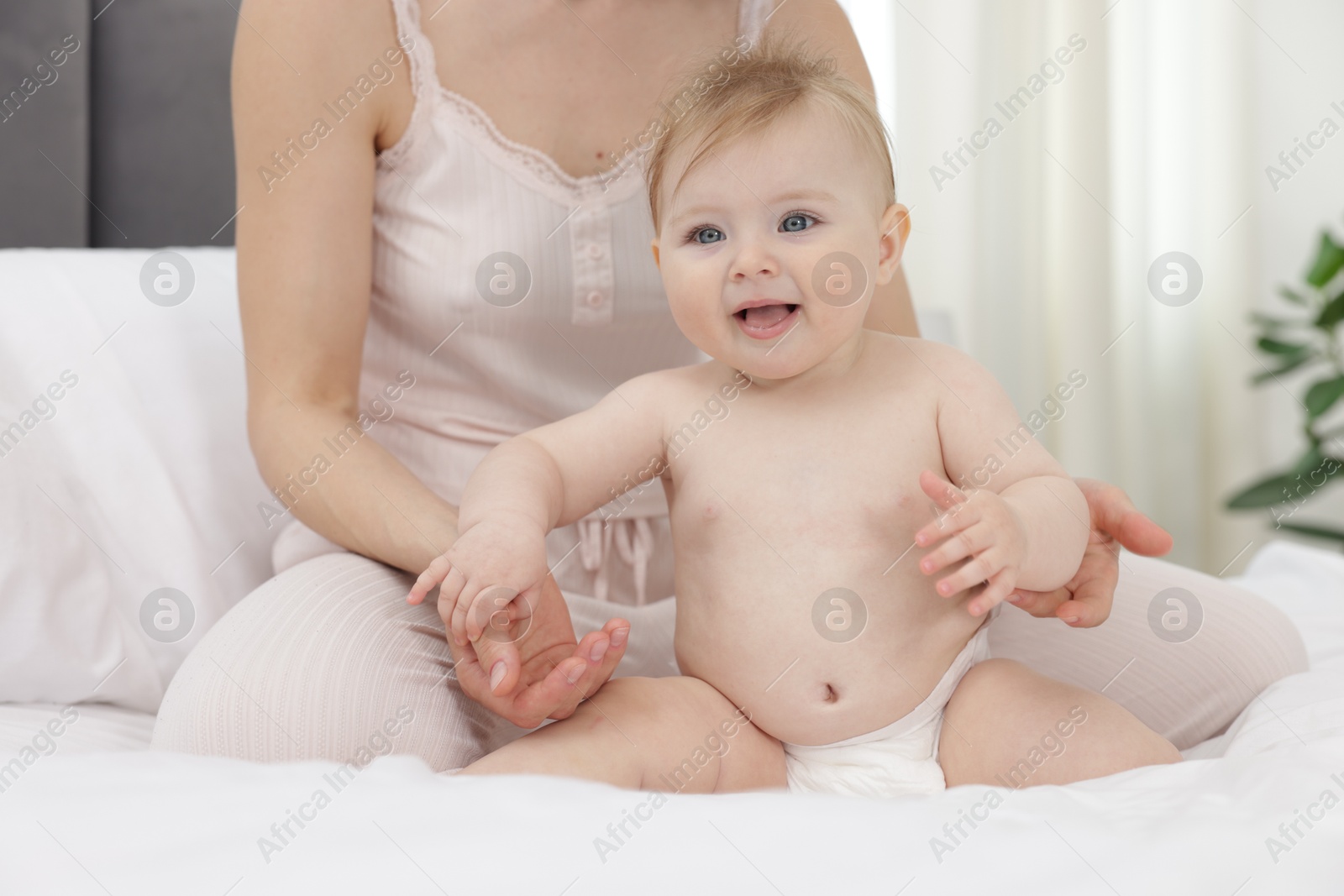 Cute little baby and mother on bed indoors, closeup Photo of Cute little baby and mother on bed indoors, closeup