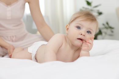 Photo of Cute little baby and mother on bed indoors, closeup