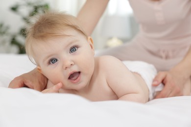 Photo of Cute little baby and mother on bed indoors, closeup