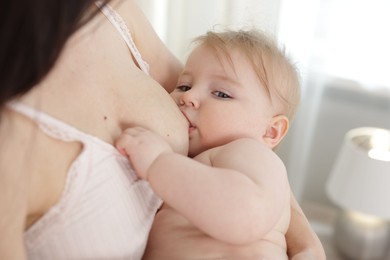 Photo of Mother breastfeeding her cute little baby indoors, closeup