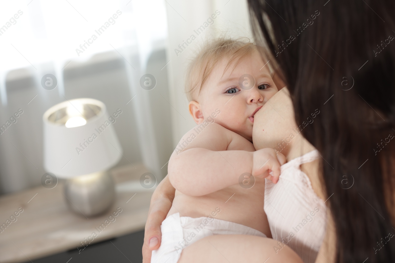 Mother breastfeeding her cute little baby indoors, closeup. Space for text Photo of Mother breastfeeding her cute little baby indoors, closeup. Space for text