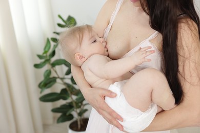 Photo of Mother breastfeeding her cute little baby indoors, closeup. Space for text