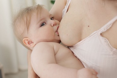 Photo of Mother breastfeeding her cute little baby indoors, closeup