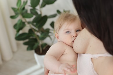 Photo of Mother breastfeeding her cute little baby indoors, closeup. Space for text