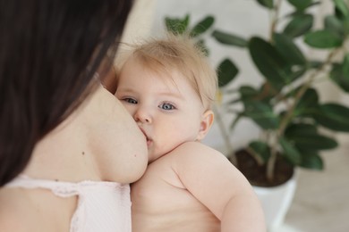Photo of Mother breastfeeding her cute little baby indoors, closeup. Space for text