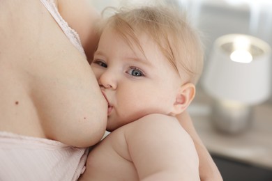 Photo of Mother breastfeeding her cute little baby indoors, closeup