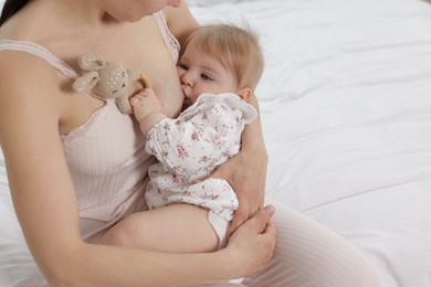 Photo of Mother breastfeeding her cute little baby on bed, closeup