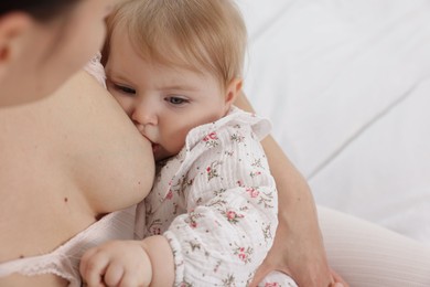 Photo of Mother breastfeeding her cute little baby on bed, closeup