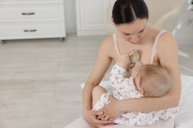 Photo of Mother breastfeeding her cute little baby indoors. Space for text
