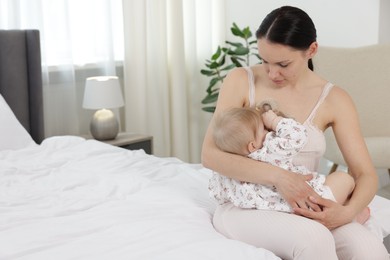 Photo of Mother breastfeeding her cute little baby on bed indoors