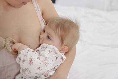 Photo of Mother breastfeeding her cute little baby on bed, closeup. Space for text