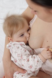 Photo of Mother breastfeeding her cute little baby on bed, closeup