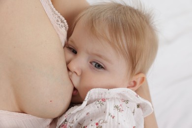 Photo of Mother breastfeeding her cute little baby on bed, closeup
