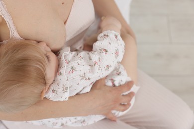 Photo of Mother breastfeeding her little baby indoors, closeup