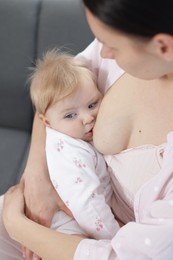 Photo of Mother breastfeeding her little baby on sofa