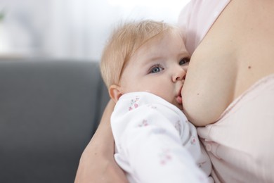 Photo of Mother breastfeeding her little baby on sofa, closeup