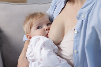 Photo of Mother breastfeeding her little baby on sofa indoors, closeup