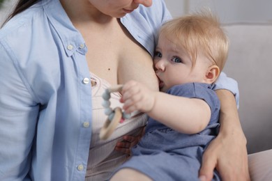 Photo of Mother breastfeeding her little baby indoors, closeup