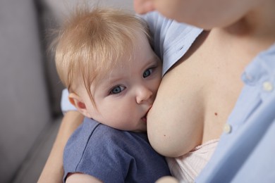 Photo of Mother breastfeeding her little baby indoors, closeup