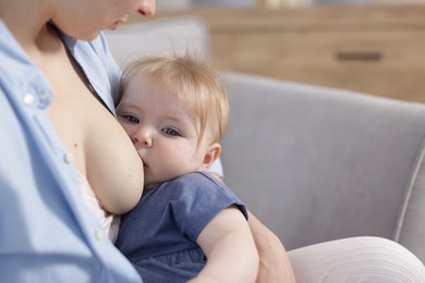 Photo of Mother breastfeeding her little baby indoors, closeup