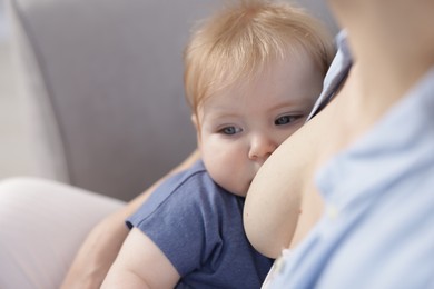 Photo of Mother breastfeeding her little baby indoors, closeup