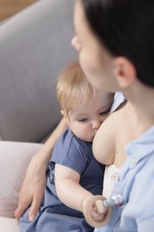 Photo of Mother breastfeeding her cute little baby indoors