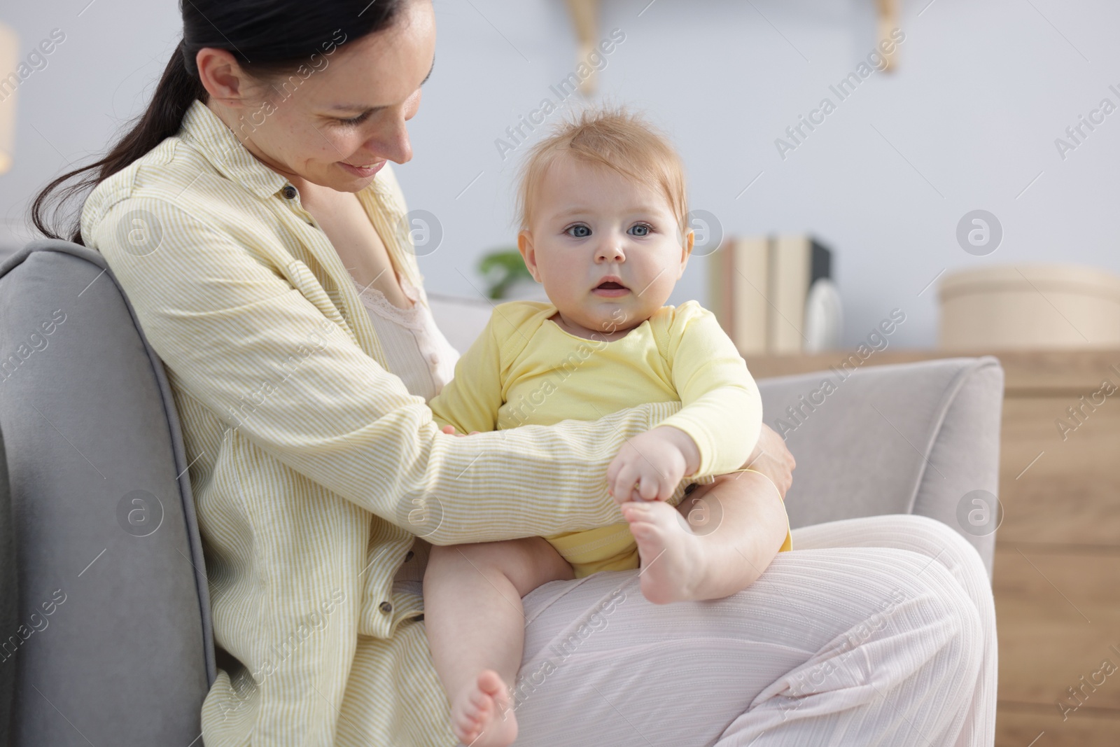 Mother with her little baby on armchair indoors Photo of Mother with her little baby on armchair indoors