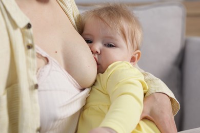 Photo of Mother breastfeeding her little baby on sofa indoors, closeup