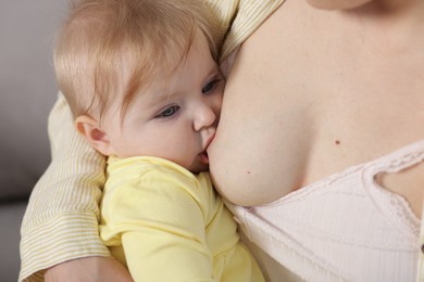 Photo of Mother breastfeeding her cute little baby indoors, closeup