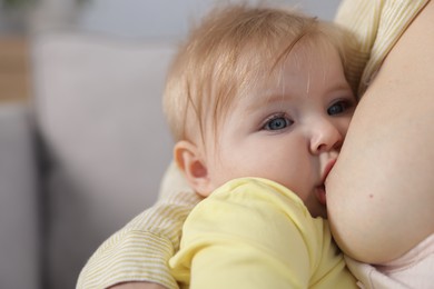 Photo of Mother breastfeeding her little baby on blurred background, closeup