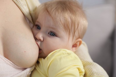 Photo of Mother breastfeeding her little baby on blurred background, closeup