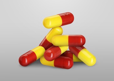 Image of Antibiotic pills. Yellow and red capsules on grey gradient background