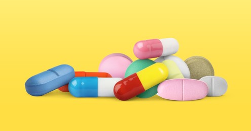 Image of Different antibiotic pills on yellow background. Banner design
