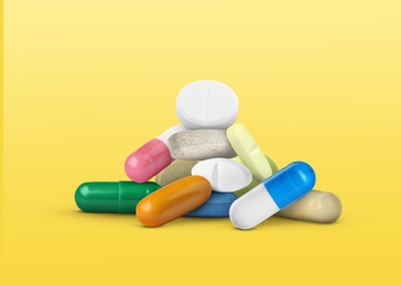 Image of Many different antibiotic pills on yellow gradient background