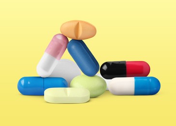 Image of Different antibiotic pills on yellow gradient background