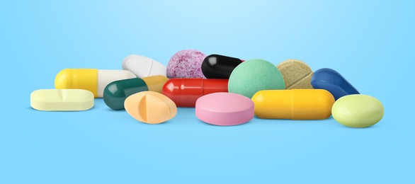 Image of Different antibiotic pills on light blue background. Banner design